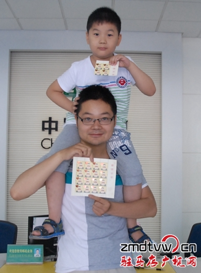 圖為6月13日，一對父子在市中心郵政所展示“感恩父親”特種郵票 .JPG